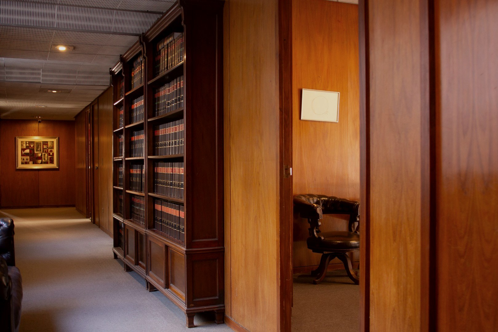 Pasillo del Estudio Okęcki, Guiroy & Pereyra Iraola con bibliotecas jurídicas de piso a techo